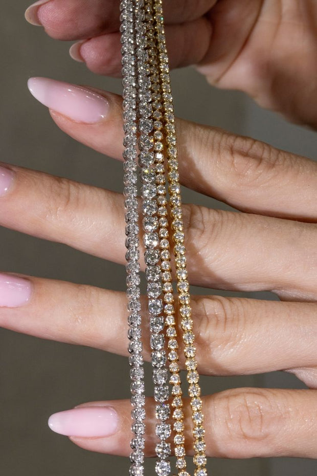 A woman holds Diamond Tennis Bracelets of different lengths. She is determining the correct length for her Diamond Tennis Bracelet.